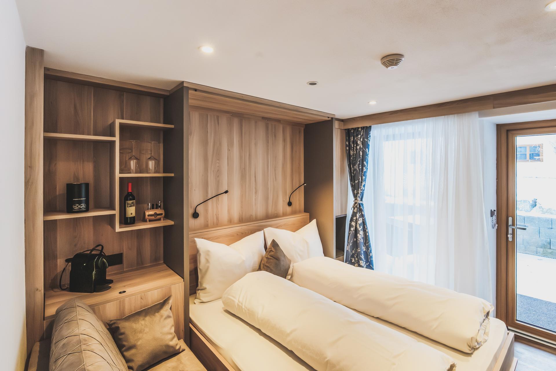 Bett mit Weinregal und Minibar im Doppelzimmer Freiraum im Ur-Genuss in Heiterwang